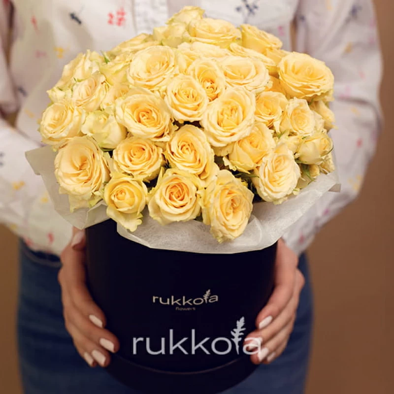 Кремовые кустовые розы в средней черной шляпной коробке